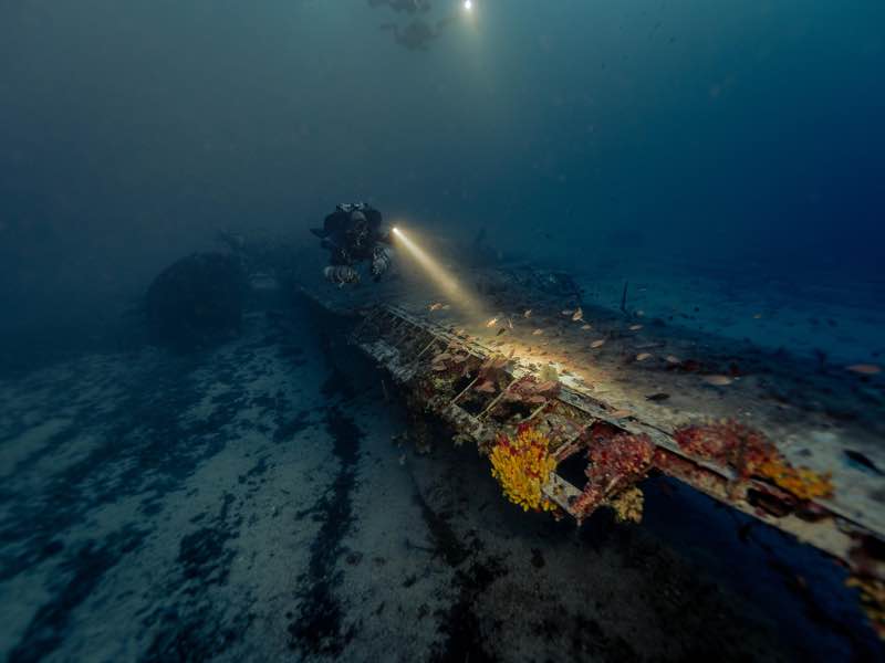 B-24 Liberator fuselage with diver torch at 57m. Photo: Jon Borg