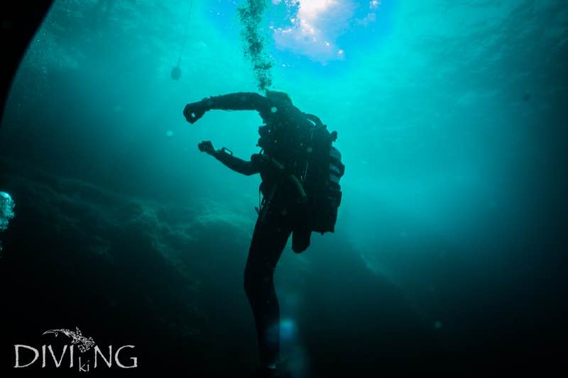 Diver silhouette against turquoise light at Zurrieq East Reef wall